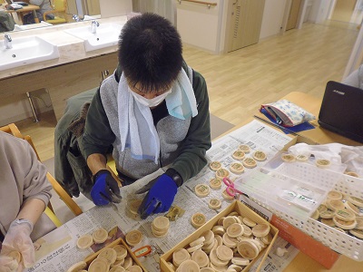 A photo of a user of the social welfare corporation Otofuke Yoseien manually attaching the key chain metal fittings one by one.