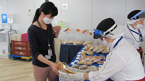 스완 베이커리 점원 씨 두 사람이 감염 예방을 위해 마스크와 얼굴 보호대를 착용하고 빵 회계를하고있는 모습의 사진