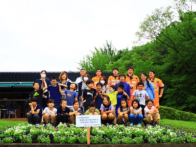 綺麗に完成した花壇の前でみんなで記念撮影をしている様子の写真