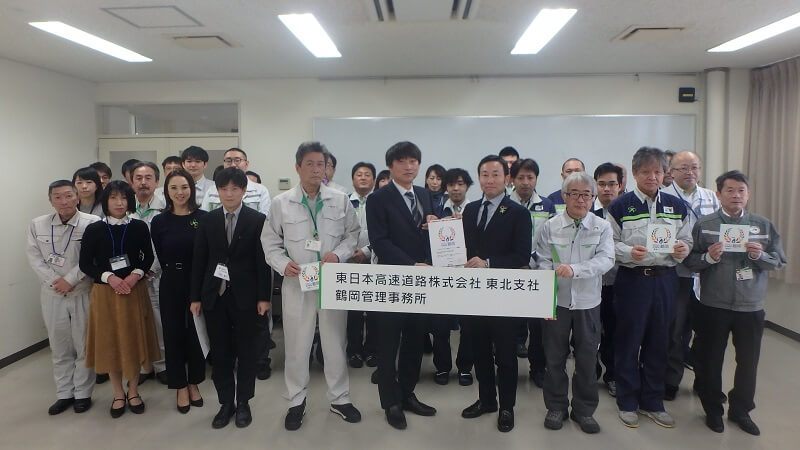 「つるおかSDGs推進パートナー」に登録され、NEXCO東日本東北支社鶴岡管理事務所とその関連グループみんなで記念撮影をしているの写真