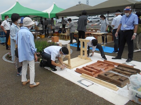 A photo of students from the Hokkaido Shirakaba High School for Special Needs demonstrating and selling how to assemble a wooden prefabricated table.
