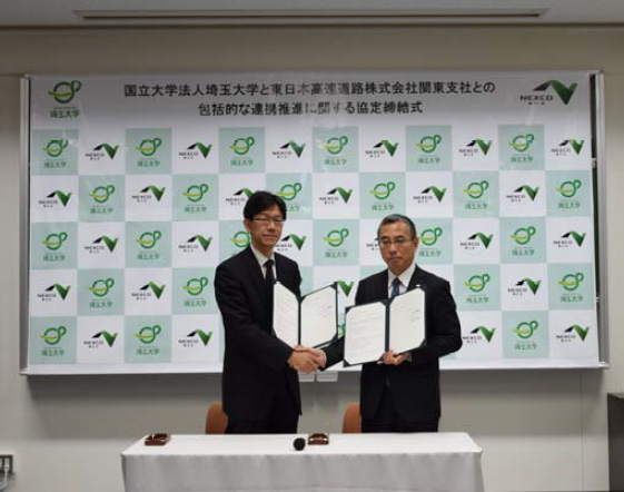 รูปภาพของประธาน Yamaguchi แห่งมหาวิทยาลัย Saitama (ซ้าย) และประธานสาขา Yokoyama สาขา NEXCO East Japan Kanto สาขา (ขวา) จับมือหลังจากเซ็นสัญญา