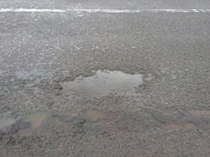 舗装面のひび割れやポットホールなどが発生している箇所の写真1